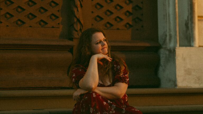 Eine Frau schaut verträumt ins Abendlicht vor dem Schloss Ludwigsburg.